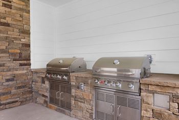 two gas bbqs on the patio of a home with white walls and brick at The Enclave at Deer Moss Creek, Niceville, 32578
